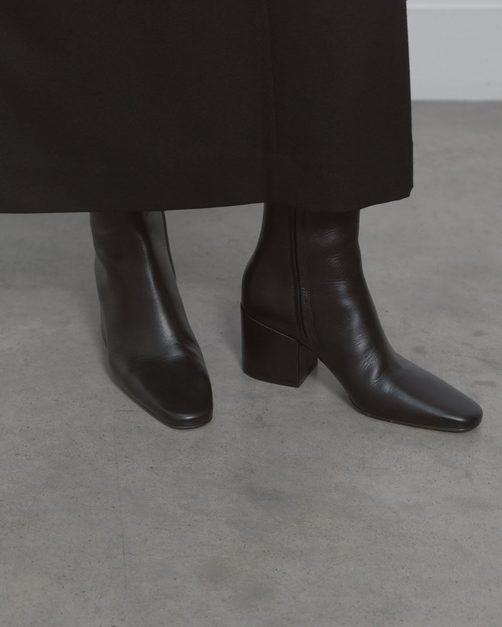 Model walking in Dear Frances Alma Ankle Boots in black leather, showing the square toe and block heel